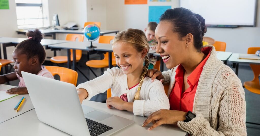 teacher reviewing the work done by a young student at a computer